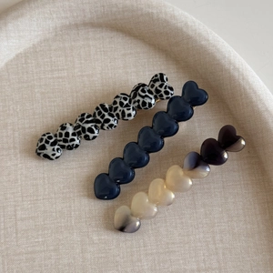 Trois pinces à cheveux en acétate en forme de cœur en noir blanc, bleu marine et beige