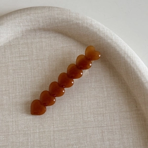 Détail de la pince à cheveux cœur ambre sur un plateau en osier au design élégant