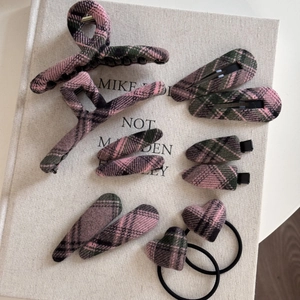 Close-up of pink and green plaid hair clip set with vintage fabric texture on a book