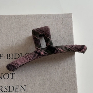 Detailed view of grey and pink plaid fabric texture on a vintage style shark hair clip