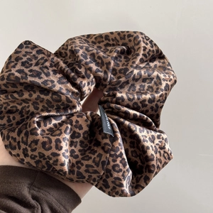 Detailed close-up of large velvet leopard print scrunchie showing glossy satin texture