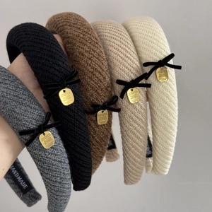 Detail of five-color thick knitted headbands with velvet bows and gold metal tags