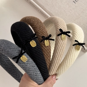 Close-up of knit headbands with black velvet bows and gold metal plates in five colors