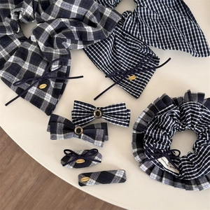 Marineblaues Karo-Haar-Accessoires-Set mit Schleife und Haargummi auf weißem Tisch