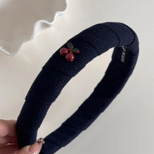 Détail d'un bandeau en velours bleu marine avec cerises faites main et étiquette artisanale