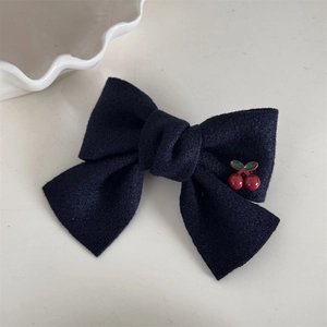 Détail d'une pince à cheveux à nœud bleu marine avec décor cerise sur fond blanc