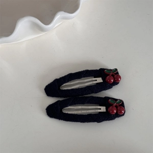 Détail de barrettes à cheveux en peluche noire avec breloques cerises en résine