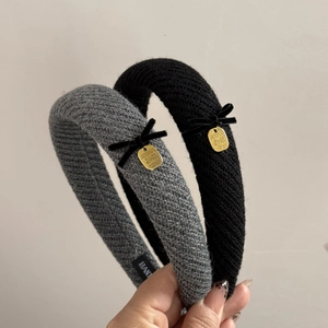 Detailed macro view of black knitted headband featuring velvet bow and golden metal charm