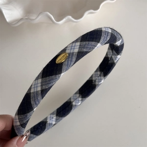 Detailansicht des dunkelblauen Karo-Haarbandes mit graviertem goldenen Metall-Logo