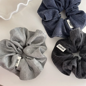 Detailed view of handmade striped scrunchies in navy, gray, and black fabric textures