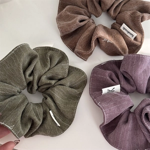 Detailed view of three herringbone textured scrunchies with white contrast stitching