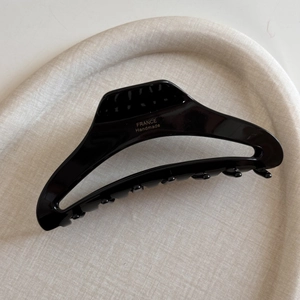 Detail of black acetate hair claw clip showing the gold France Handmade logo engraving