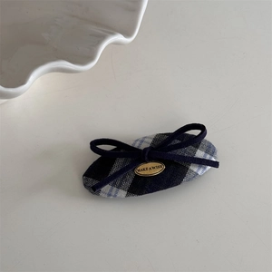 Detail der marineblauen Karo-Haarspange mit Schleife und goldener Plakette mit Gravur