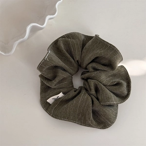 Detailed macro view of olive green retro striped scrunchie with soft fabric texture