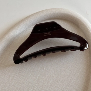 Detailed macro view of deep burgundy acetate hair claw clip with golden handmade lettering