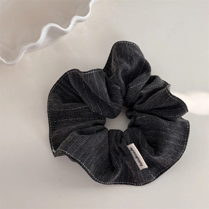 Detail of dark grey striped fabric hair scrunchie with handmade label and denim texture
