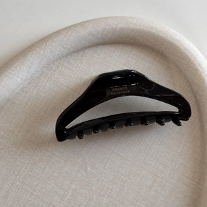 Detail of glossy black acetate hair claw with golden France Handmade lettering detail