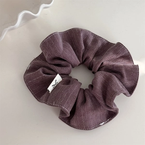 Detailed view of dark purple herringbone scrunchie with minimalist logo tag