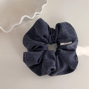 Detail of dark blue striped scrunchie with white stitching and retro denim texture