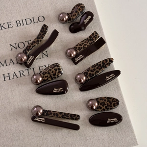 Detail of leopard print hair clips with champagne pearls and gold lettering