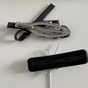 Detail view showing back mechanism and texture of grey fabric bow and rectangular hair clips