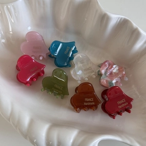 Close-up of colorful heart-shaped acetate mini hair clips neatly arranged in a shell plate