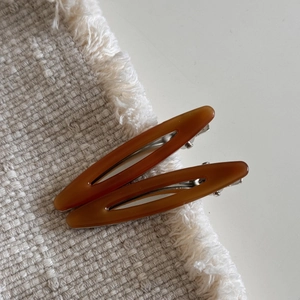 Gros plan de pinces à cheveux en acétate ambre ajouré avec clip en métal sur tissu