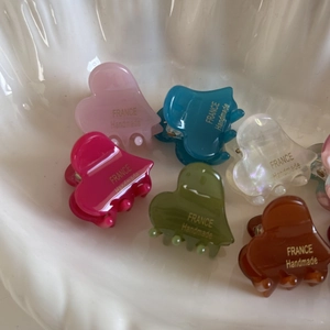 Detailed macro view of heart-shaped mini hair clips in various bright glossy colors