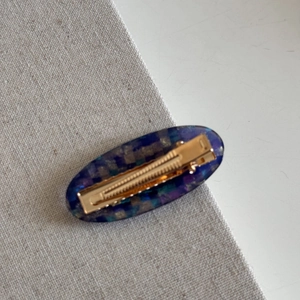Detailed view of the golden metal spring clip mechanism on the marble pattern hair clip