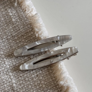Détail de pinces à cheveux en acétate marbré posées sur un tissu doux élégant