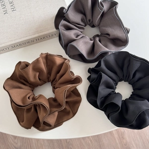 Detailed texture of ruffled fabric hair scrunchies in brown, taupe and black colors