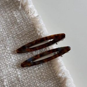 Vue détaillée de la pince à cheveux en acétate écaille sur un tissu blanc à franges