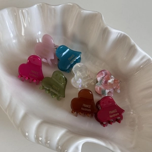 Close-up of eight acetate heart-shaped hair claws with FRANCE Handmade engraving in a tray