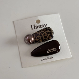 Detail of leopard print hair clip set with champagne pearls on a branded display card
