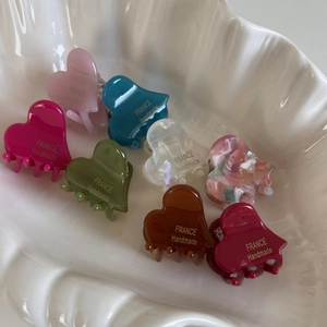 Macro detail of assorted acetate heart hair claws in multiple colors on a shell plate