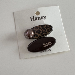 Detail of leopard print and coffee brown hair clips with gold lettering on display card