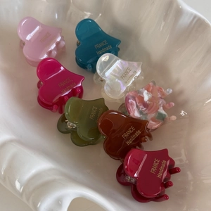 Eight colorful heart-shaped acetic acid hair claws in a decorative shell tray