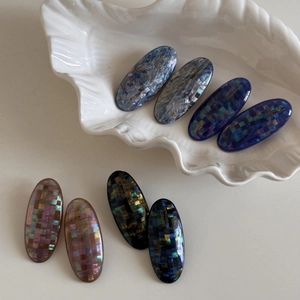 Close-up of handmade oval hair clips with iridescent checkered mosaic pattern