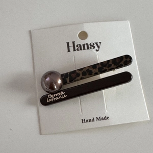 Close-up of leopard print and champagne pearl hair clips set on a white brand card