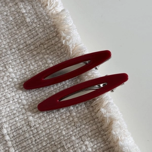 Détail de pinces à cheveux en acétate rouge ajouré avec base en métal argenté