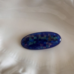 Macro detail of blue oval hair clip with colorful mosaic sequins and gold France Handmade logo