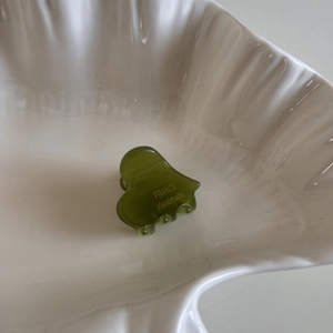 Close-up of heart-shaped olive green acetate hair claw clip with handmade engraving