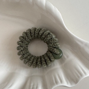 Dettaglio dell'elastico a spirale in ciniglia verde oliva su piatto decorativo bianco