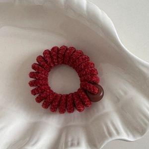 Dettaglio dell'elastico a spirale in ciniglia rossa con perla in piatto a conchiglia