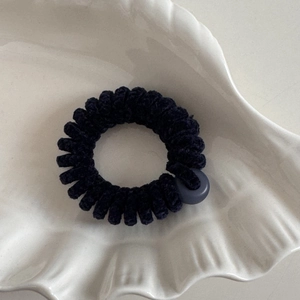 Dettaglio di elastico a spirale in ciniglia blu navy su un vassoio in ceramica bianca