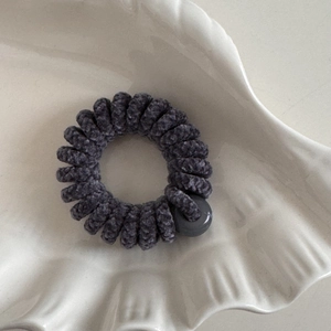 Dettaglio dell'elastico a spirale in velluto di ciniglia grigio scuro su vassoio