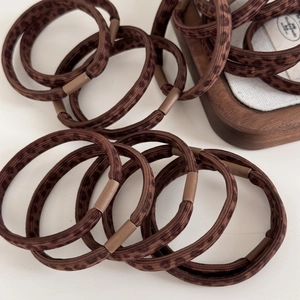 Close-up of brown leopard print hair elastics with durable connectors on wooden tray