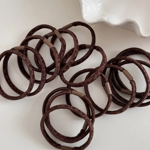 Close-up of brown leopard print hair ties with matte plastic buckles on white surface