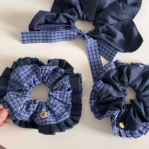Detail view of blue plaid and denim scrunchies set with wooden buttons and gold tag