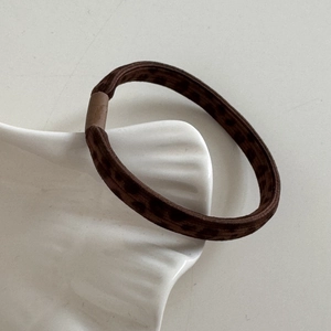 Detailed close-up of brown leopard print hair tie on a white shell ceramic tray